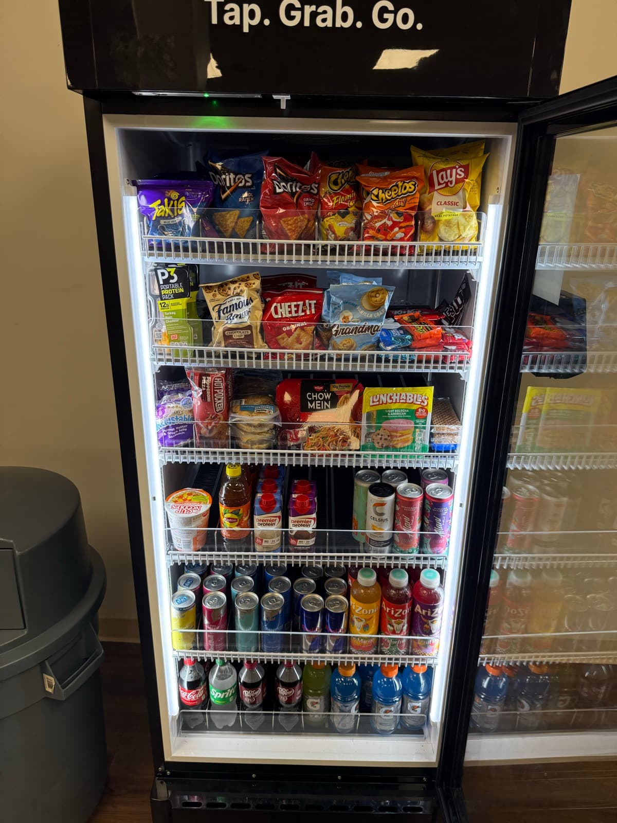Open smart cooler stocked with chips, drinks and fresh food